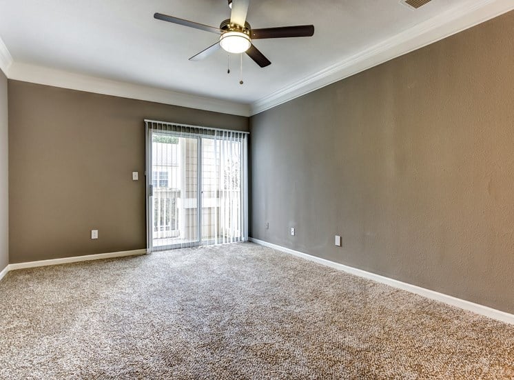 Upgraded living area with crown molding, carpet, and sliding glass door that leads to balcony